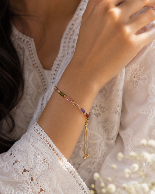 Model wearing the VIYOMA Prism Line Bracelet with delicate lace attire, showcasing colorful baguette crystals and an adjustable gold chain.