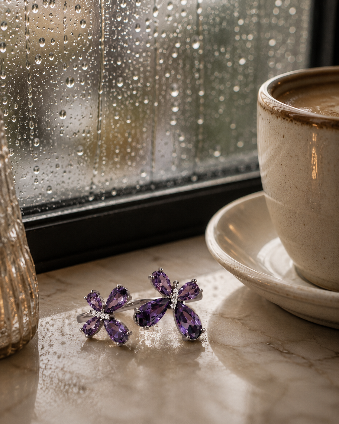 VIYOMA Butterfly Rift Ring with sparkling violet crystals displayed beside a coffee cup near a rain-covered window, creating a cozy and elegant lifestyle setting.